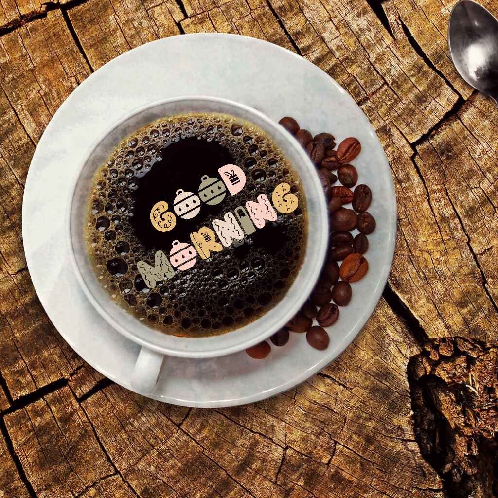 a cup of coffee on a wooden background with coffee beans and "good morning " written on top.
